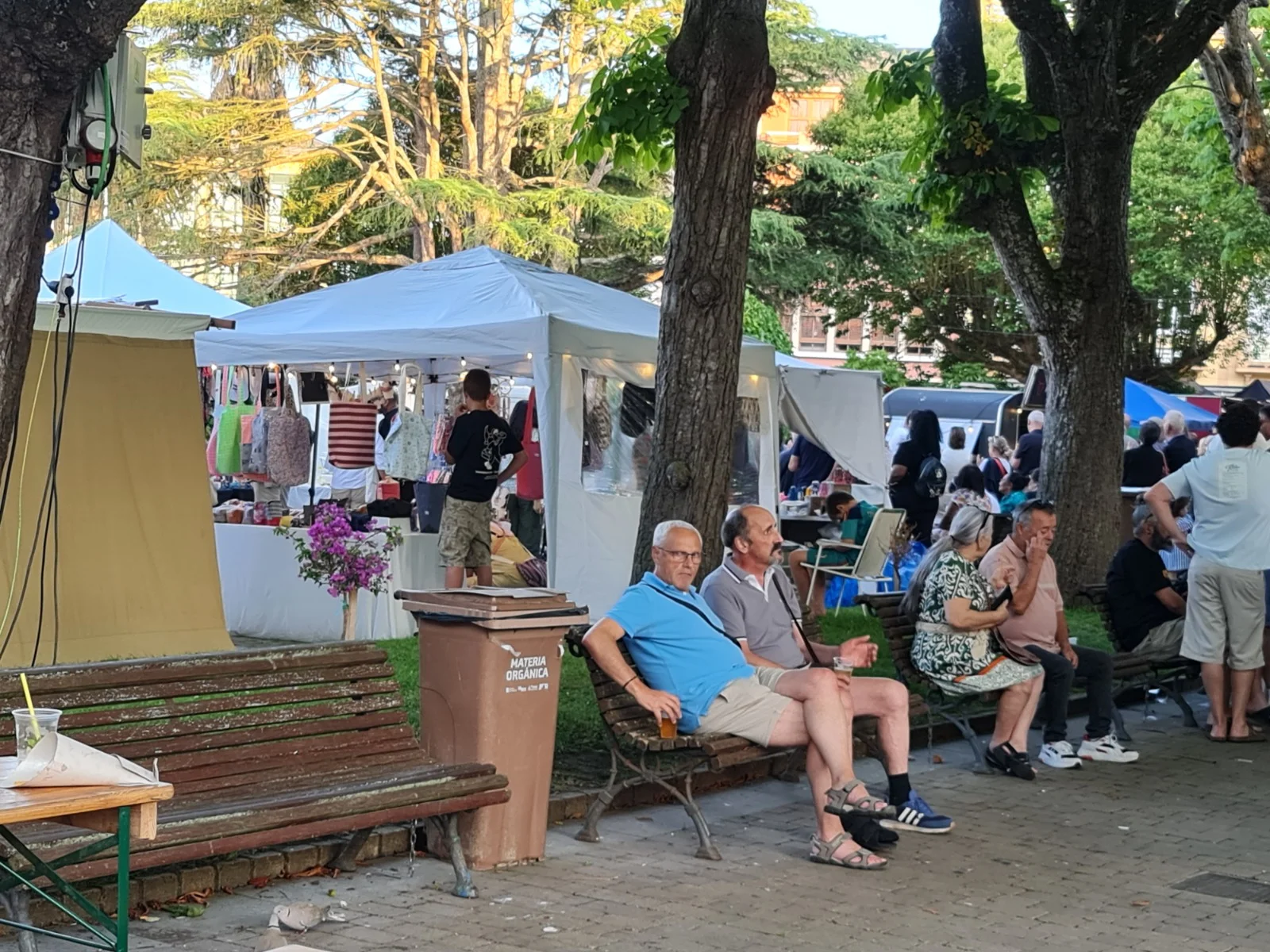 Feria de artesanía entre árboles con visitantes y expositores